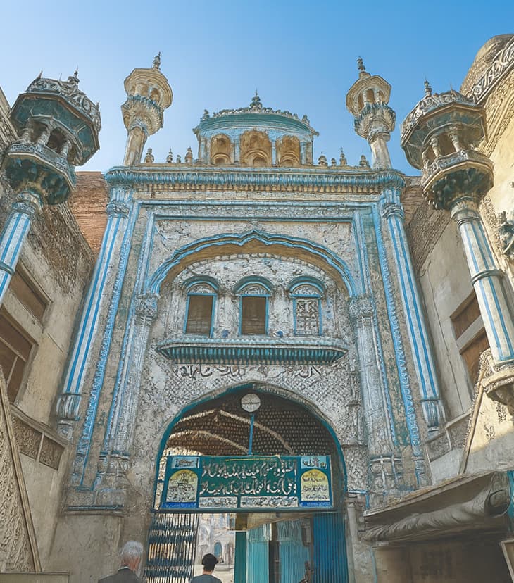 Ancient mosque featuring traditional Islamic architectural elements with weathered stone walls, arched doorways, and historic minarets