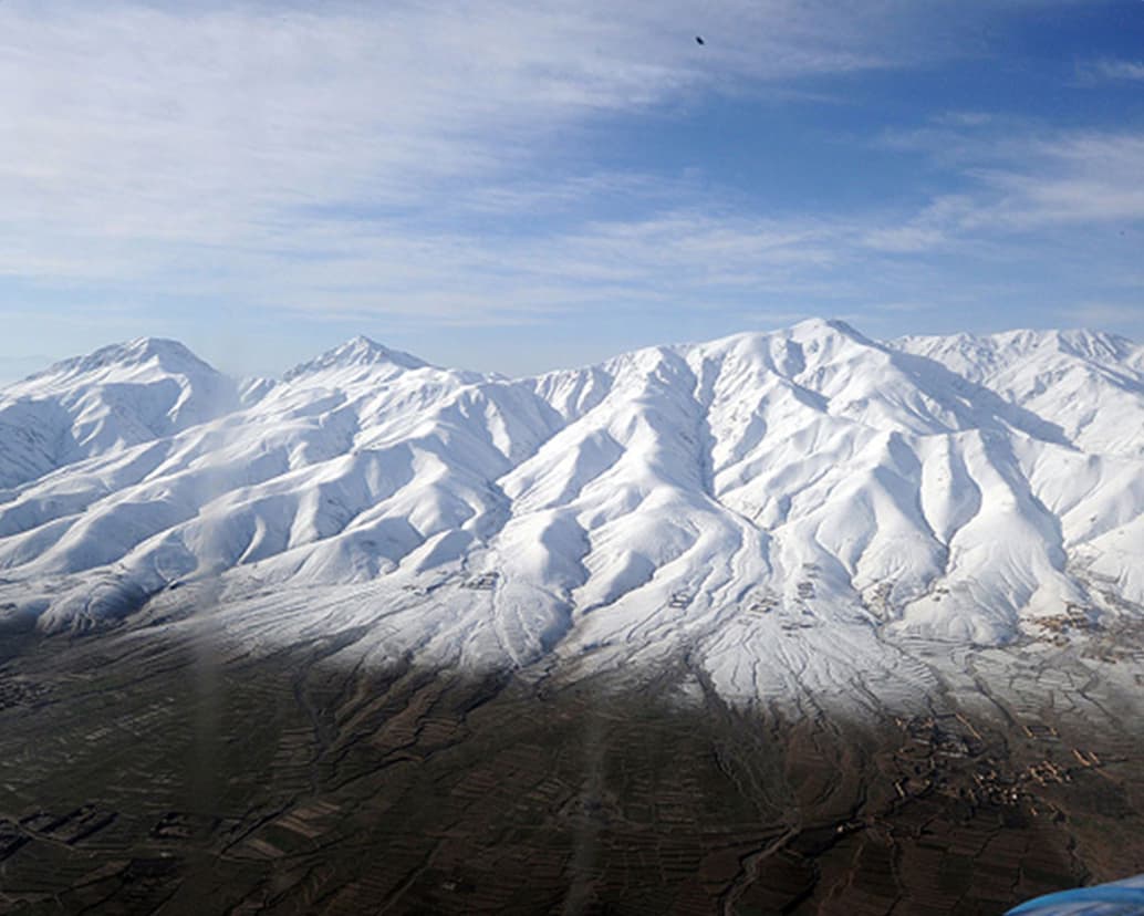 Majestic mountains of Khyber Pakhtunkhwa with towering snow-covered peaks, lush green foothills, and winding rivers in the valleys.