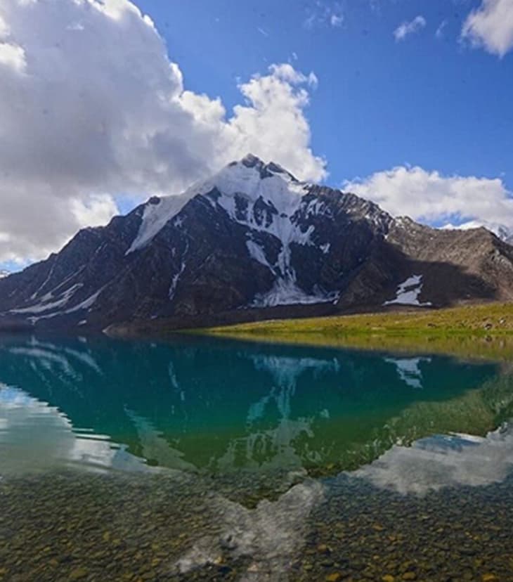 Brokhil Pass and Karambar Lake in Khyber Pakhtunkhwa, featuring crystal-clear turquoise waters surrounded by snow-capped mountains, alpine meadows, and serene wilderness at the Pakistan-Afghanistan border.
