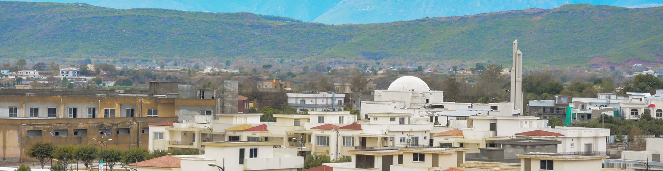 Beautiful mosque featuring a distinctive round dome nestled among residential houses with the verdant Margalla Hills providing a stunning natural backdrop
