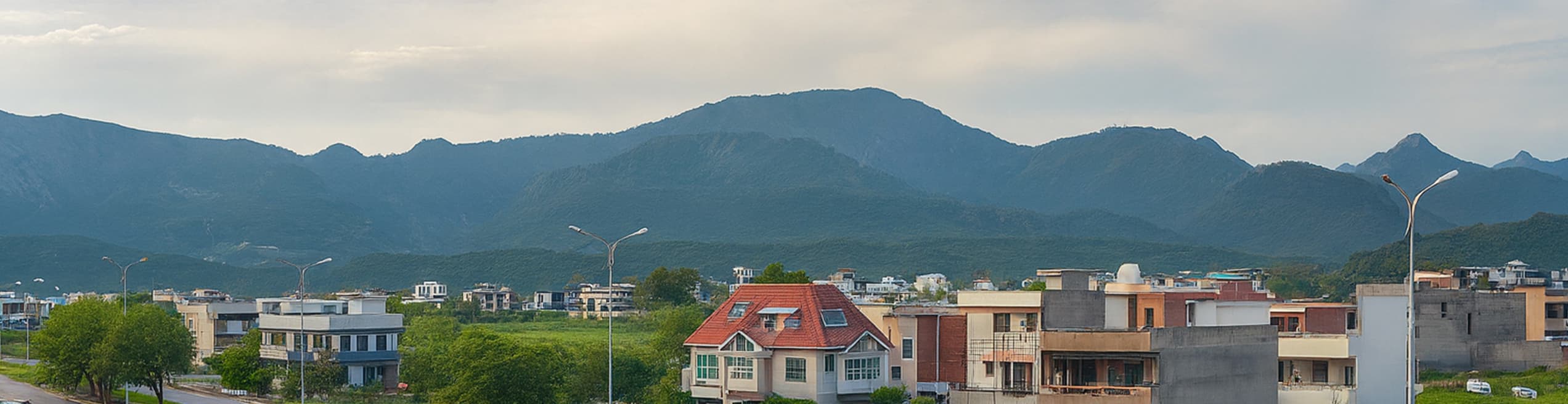 Panoramic skyline view of D-12 residential area showcasing houses against the backdrop of Margalla Hills' lush green mountainous landscape