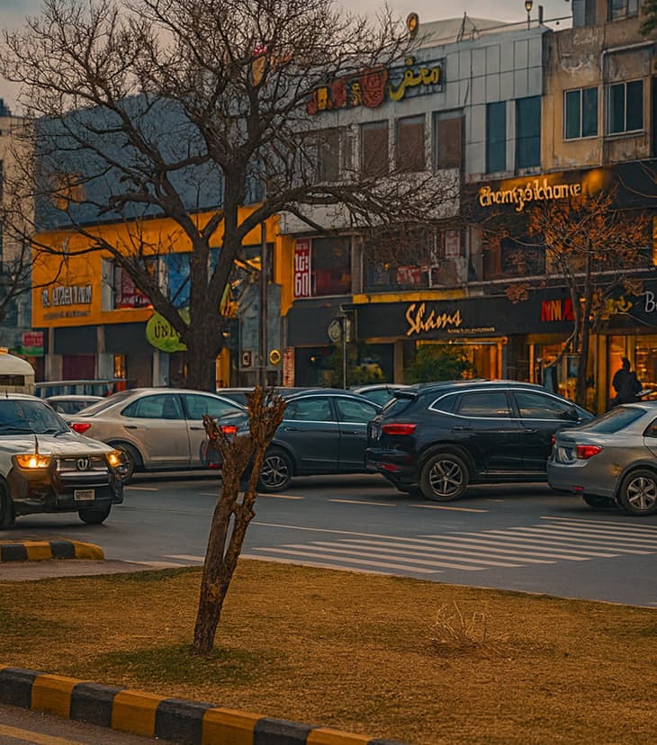 Busy street view of Jinnah Super Market in F-6, featuring shops, pedestrians, and parked cars in the main commercial area.