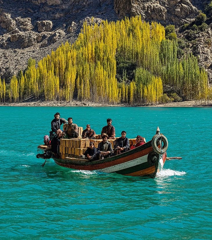 Tourists boating on the clear blue waters of Sadpara Lake in Skardu surrounded by mountains.
