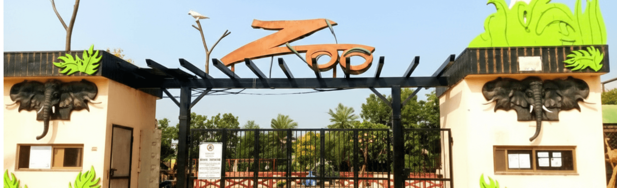 Wide banner view of Bahria Enclave Zoo park area in Islamabad with visitor spaces and enclosures, Fun places in Islamabad family day scene at Bahria Enclave Zoo with pathways and greenery