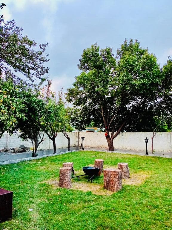 Outdoor garden with tree logs and barbecue system in Skardu, Open air BBQ space at Shah Hujra