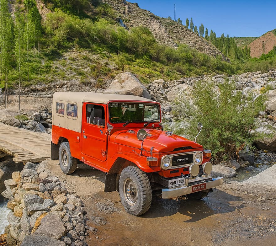 Jeep on Mountainous Roads in Basho Valley A jeep driving along winding mountainous roads in Basho Valley, surrounded by rugged peaks and scenic views.