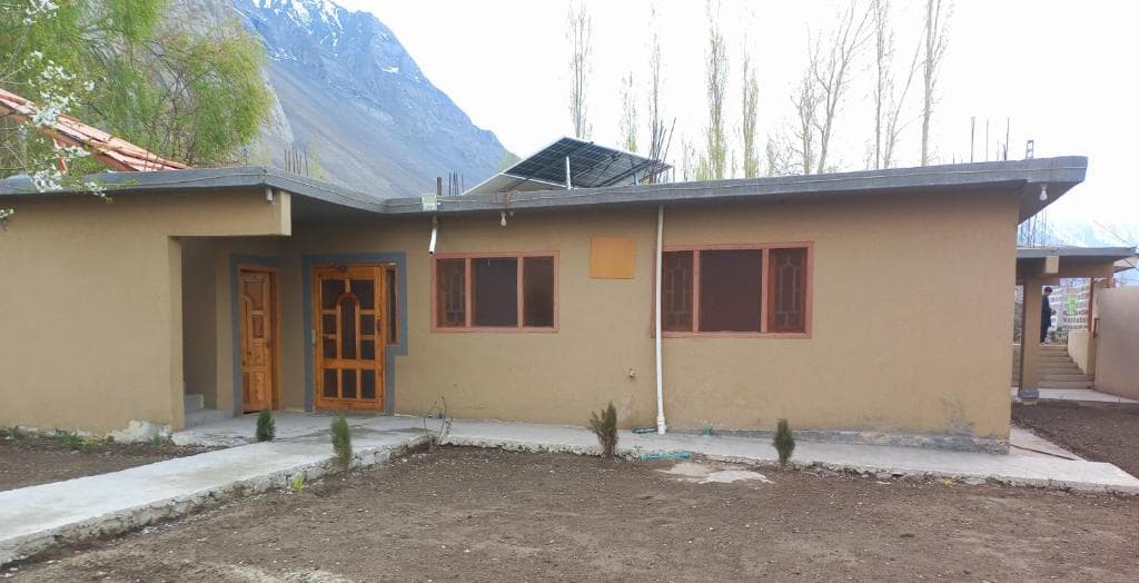 Valhalla Guest House exterior with mountains and solar panels Guest house building with mountain backdrop and solar panels in Skardu, Scenic hotel view with rooftop solar system