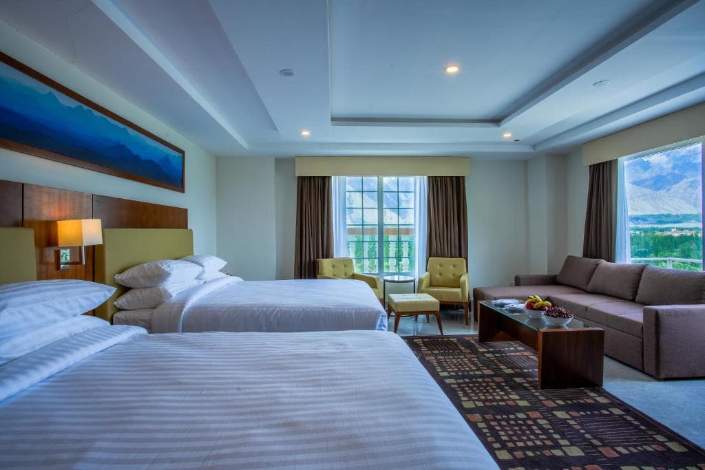 Twin room with large windows and sofa at Avari Xpress Skardu Two single beds with large windows and mountain view in Skardu, Sofa seating area inside twin room at Avari Xpress