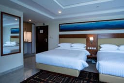 Twin bedroom with entrance view at Avari Xpress Skardu Twin beds with bedside lamps and sockets in Skardu hotel, Room entrance and two beds at Avari Xpress