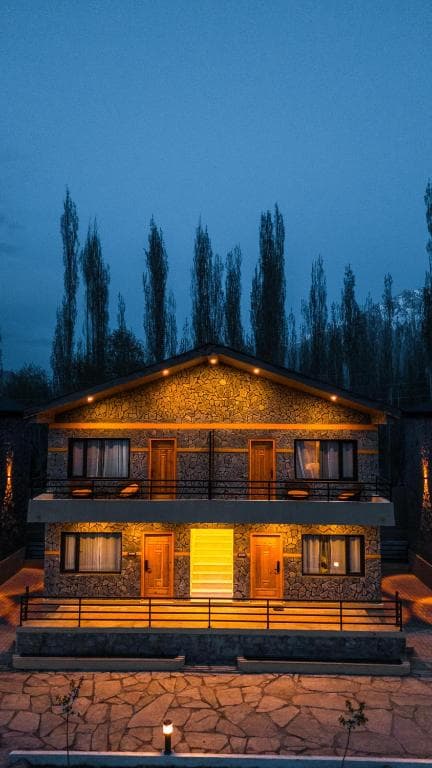 Night exterior view of Qayam Skardu with lights Hotel exterior at night with yellow lights and trees in Skardu, Illuminated facade of Qayam Skardu